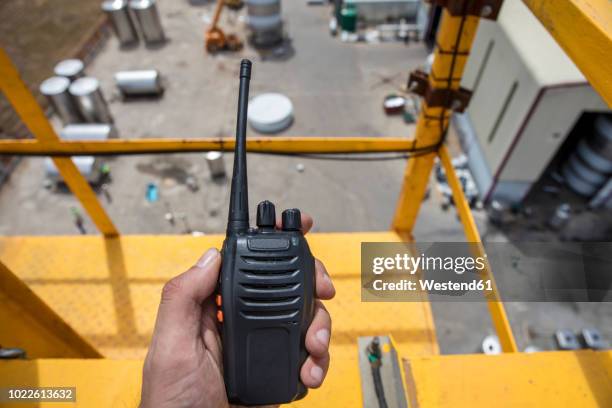 hand holding walkie talkie on top of a crane on construction site - point of view stock pictures, royalty-free photos & images