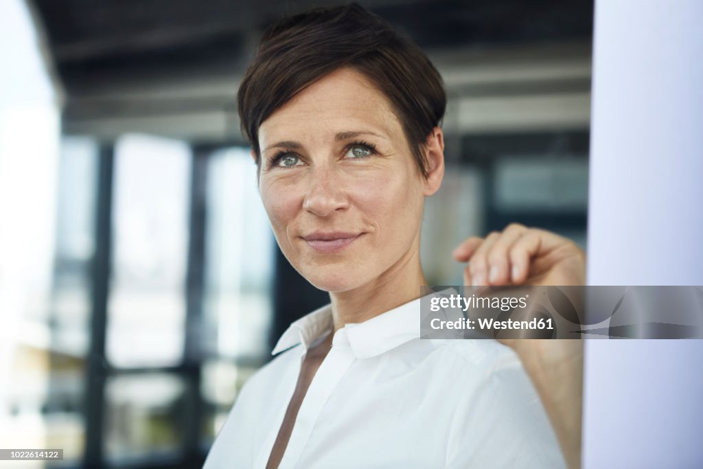 Portrait of smiling businesswoman in office looking out of window