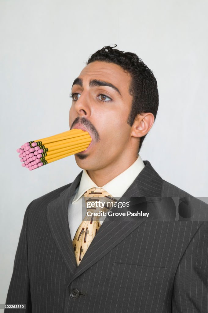 Businessman with a mouth full of pencils