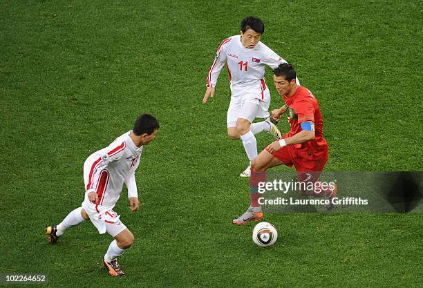 Cristiano Ronaldo of Portugal charges through Mun In-Guk and Pak Chol-Jin of North Korea during the 2010 FIFA World Cup South Africa Group G match...