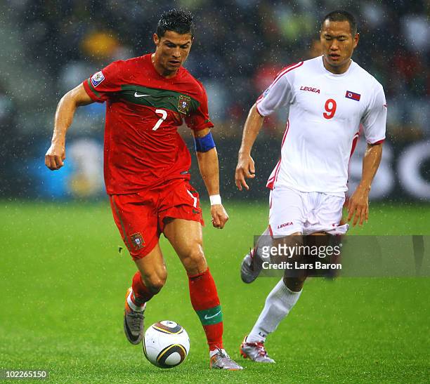 Cristiano Ronaldo of Portugal runs with the ball as Jong Tae-Se of North Korea looks on during the 2010 FIFA World Cup South Africa Group G match...