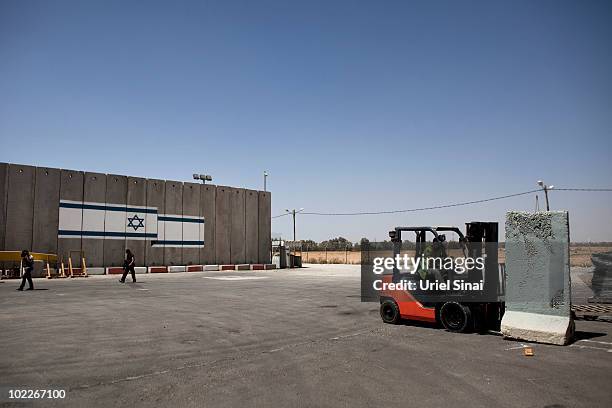 Worker loads a concrete barrier with a forklift as goods are brought to the Kerem Shalom terminal for the Gaza Strip, on June 21, 2010 on the border...