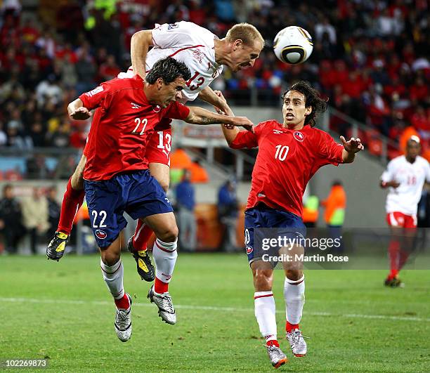 Stephane Grichting of Switzerland heads the ball under pressure from Esteban Paredes and Jorge Valdivia of Chile during the 2010 FIFA World Cup South...