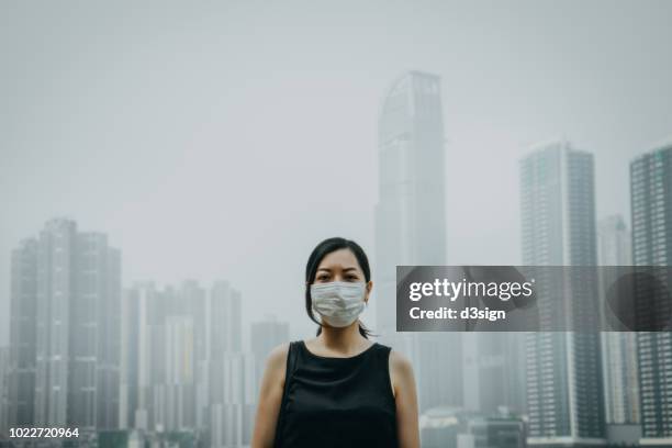 young woman wearing protective face mask in city due to the polluted air - air pollution mask stockfoto's en -beelden