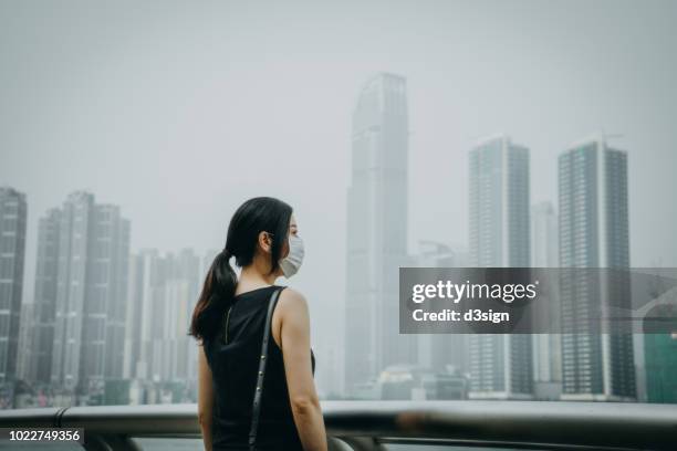 Young woman wearing protective face mask in city due to the polluted air