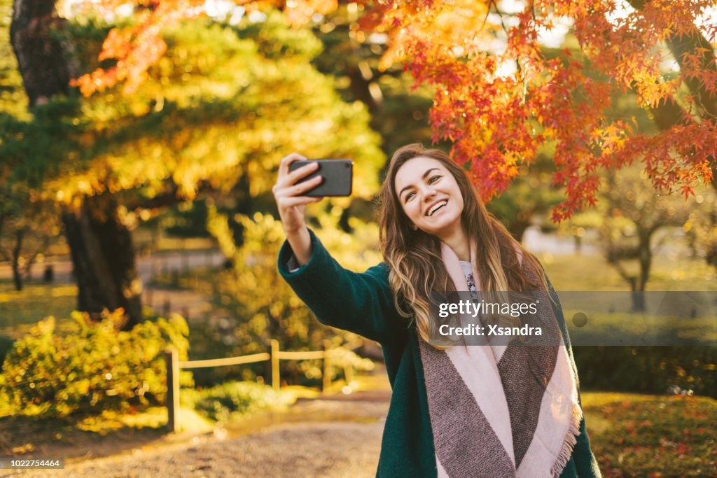 Donna felice che scatta selfie in un giardino giapponese
