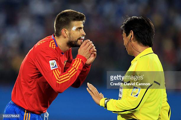 Gerard Pique of Spain speaks to referee Yuichi Nishimura with a bandage in his mouth after he was kicked in the face during the 2010 FIFA World Cup...