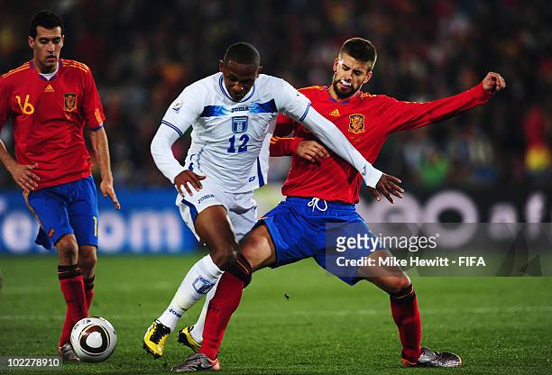 Roger Espinoza of Honduras is challenged by Gerard Pique of Spain as Sergio Busquets of Spain looks on during the 2010 FIFA World Cup South Africa...