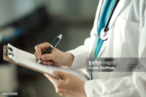 doctor writing on clipboard - parte del cuerpo humano fotografías e imágenes de stock