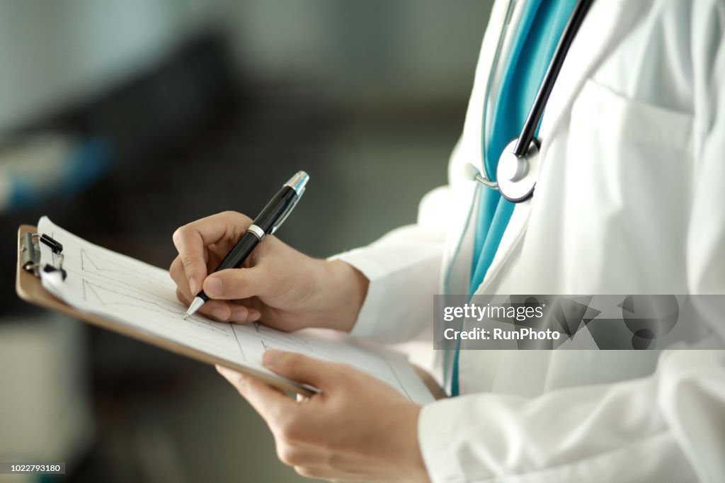 Doctor writing on clipboard