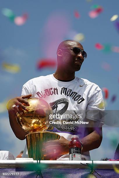 Confetti thrown from the crowd falls around Los Angeles Lakers guard Kobe Bryant as he holds the championship trophy while riding in the victory...