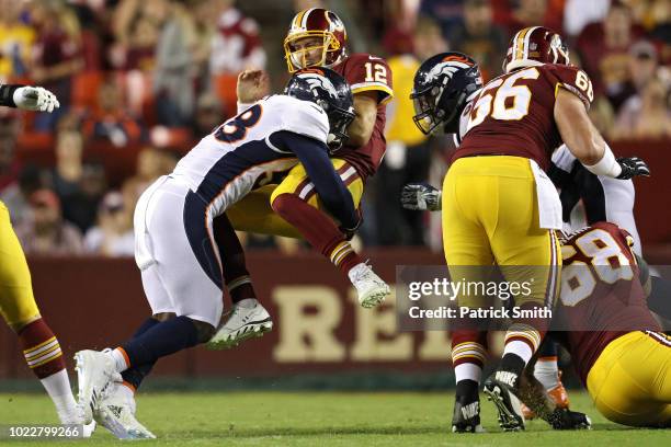 Quarterback Colt McCoy of the Washington Redskins takes a hit after releasing a pass by linebacker Von Miller of the Denver Broncos in the first half...