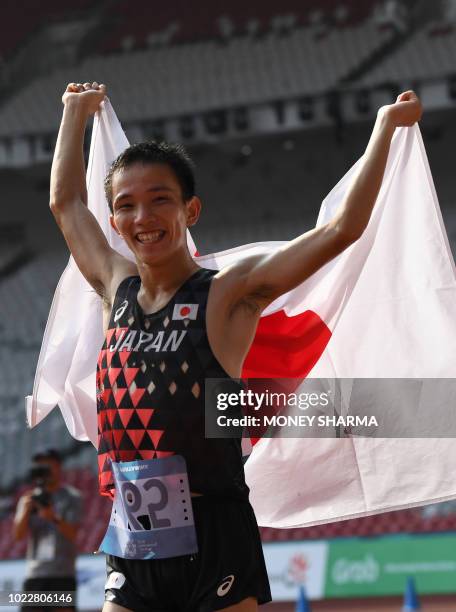 Japan's Hiroto Inoue holds his national flag after winning the men's marathon athletics event during the 2018 Asian Games in Jakarta on August 25,...