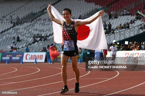 Japan's Hiroto Inoue holds his national flag after winning the men's marathon athletics event during the 2018 Asian Games in Jakarta on August 25,...