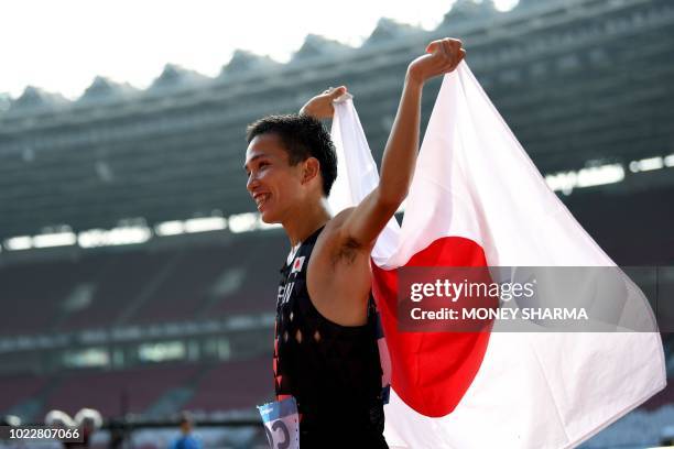 Japan's Hiroto Inoue holds his national flag after winning the men's marathon athletics event during the 2018 Asian Games in Jakarta on August 25,...