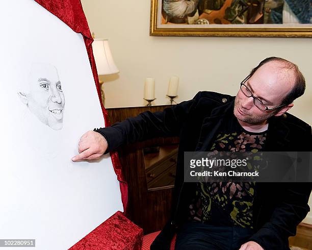 Artist, David Ilan, shows the placement of the dot he added for Dr. Maya Angelou in support of The Michael Jackson Tribute Portrait at the home of...