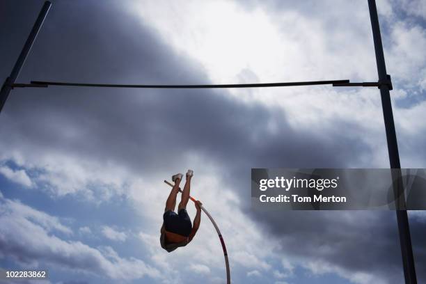 pole vaulter in mid-air - pole vault bar stock pictures, royalty-free photos & images