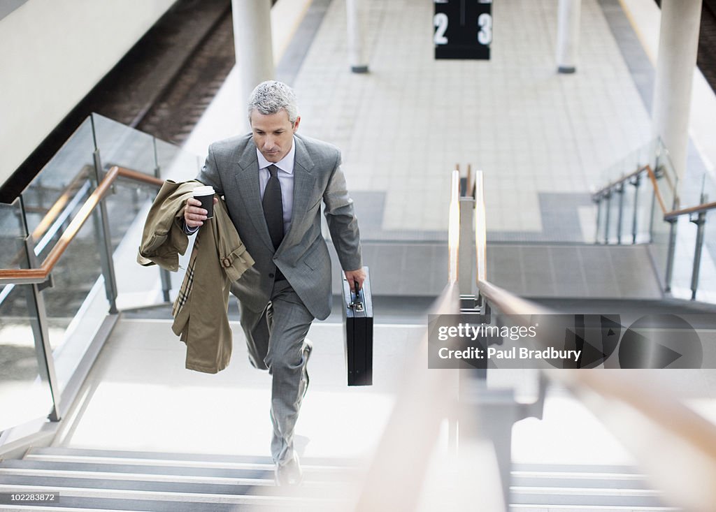 Hombre de negocios caminando hasta las escaleras en la estación de tren