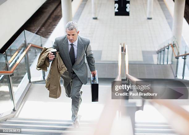 businessman walking up stairs in train station - attaché stockfoto's en -beelden