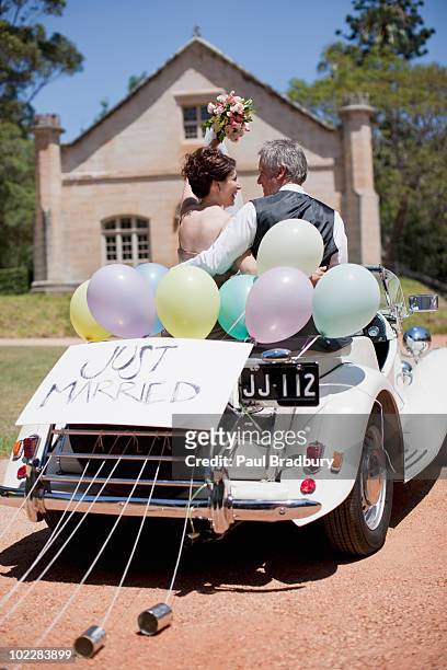 mature bride and groom riding in convertible - just married car stockfoto's en -beelden