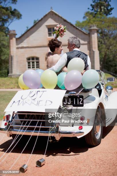 mature bride and groom riding in convertible - just married stock pictures, royalty-free photos & images