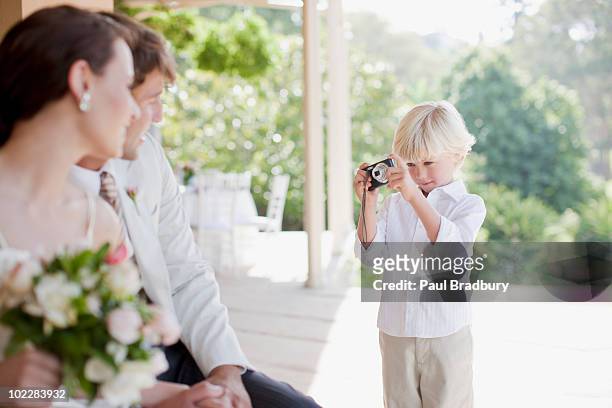 boy taking picture of bride and groom - kind camera bloemen stockfoto's en -beelden