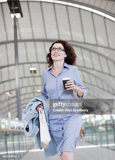 businesswoman walking and holding coffee - running refreshment stock pictures, royalty-free photos & images