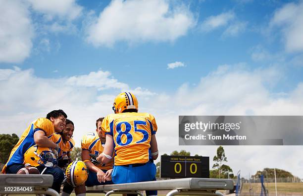 football players resting on bench - football bench stock pictures, royalty-free photos & images