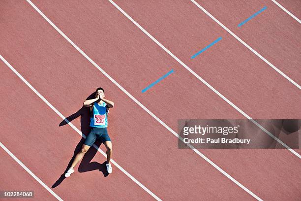 tired runner laying on track - sportman stockfoto's en -beelden