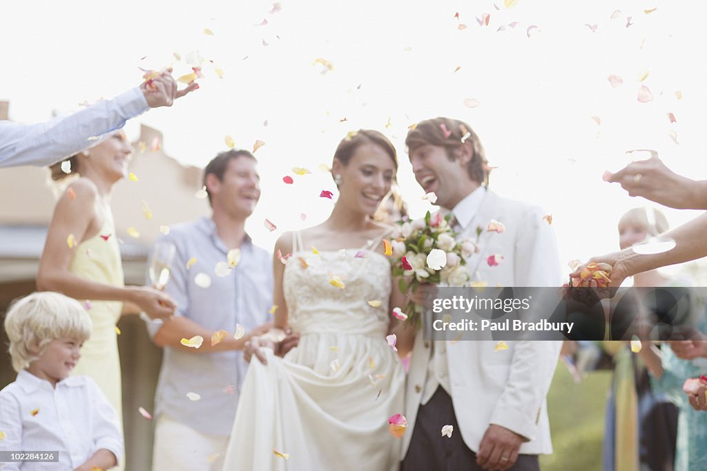 Guests throwing rose petals on bride and groom