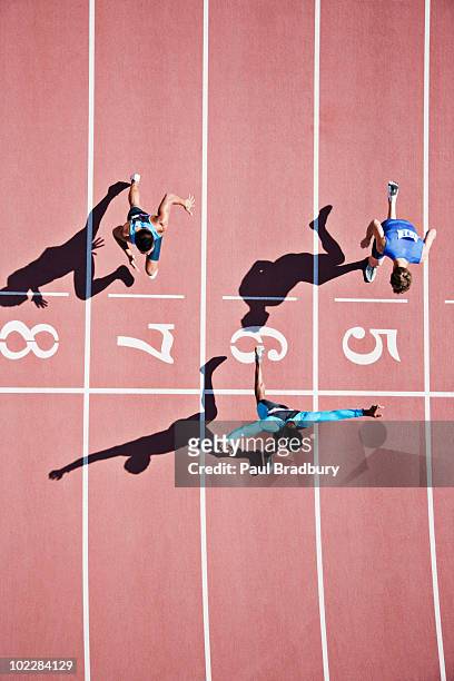 runner crossing finishing line on track - rivaliteit stockfoto's en -beelden