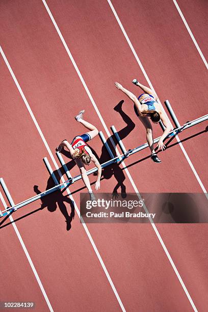 runners jumping hurdles on track - hordelopen atletiekonderdeel stockfoto's en -beelden