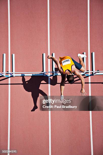 runner jumping hurdles on track - hordelopen atletiekonderdeel stockfoto's en -beelden