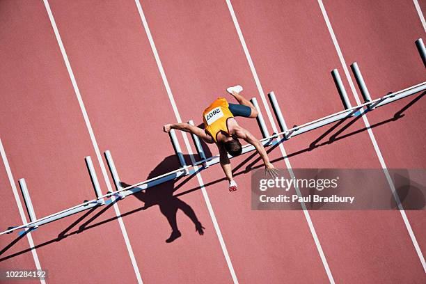 runner jumping hurdles on track - men's track stockfoto's en -beelden