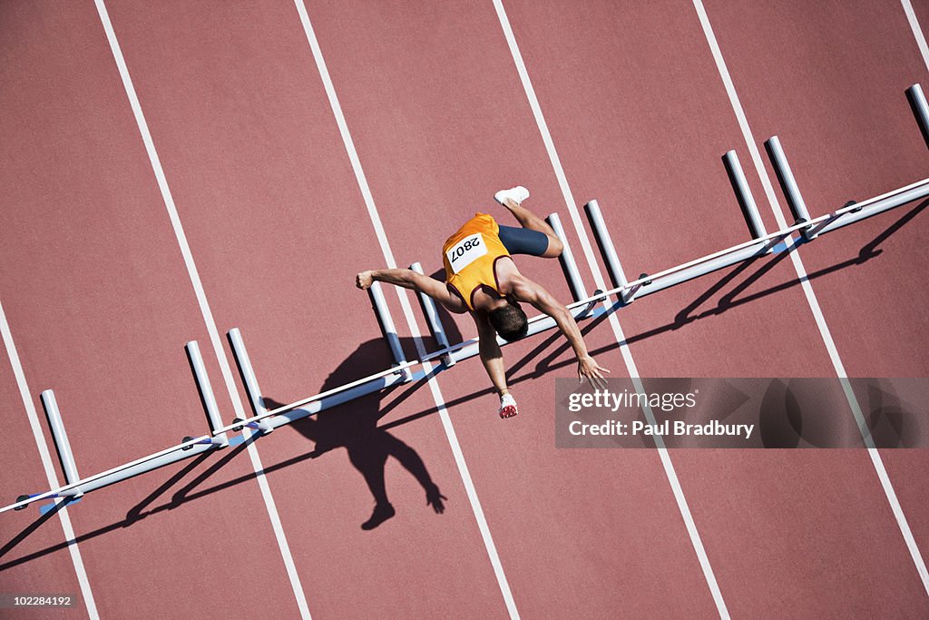 Runner jumping hurdles on track