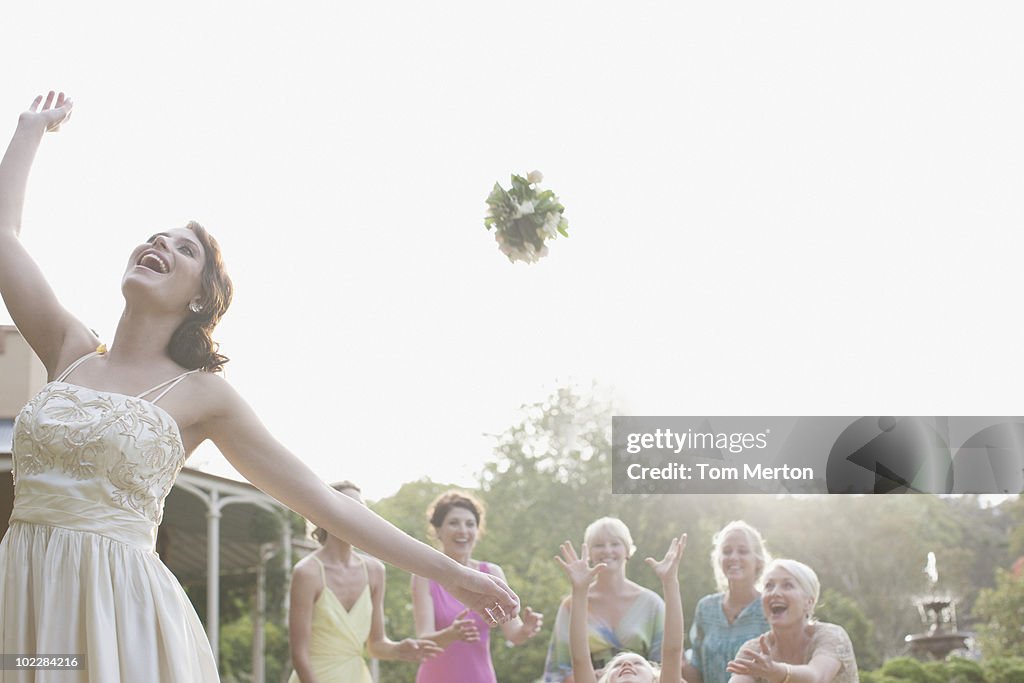 Bride throwing bouquet at wedding reception