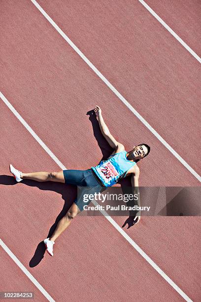 tired runner laying on track - athlete defeat stock pictures, royalty-free photos & images