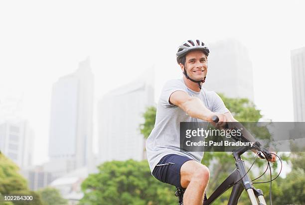 man riding bicycle in urban park - man wearing helmet stock pictures, royalty-free photos & images