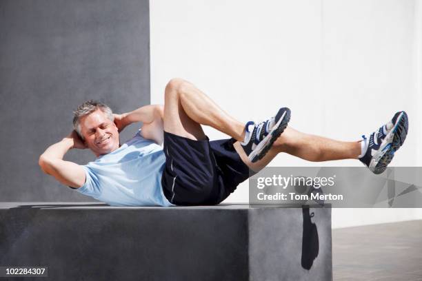 hombre haciendo sit ups en entorno urbano: - entrenamiento de fuerza fotografías e imágenes de stock