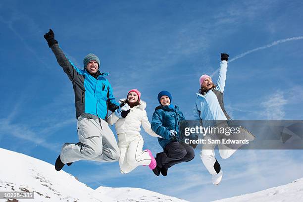 family jumping in mid-air in snow - father and mother with their daughter playing in the snow stock pictures, royalty-free photos & images