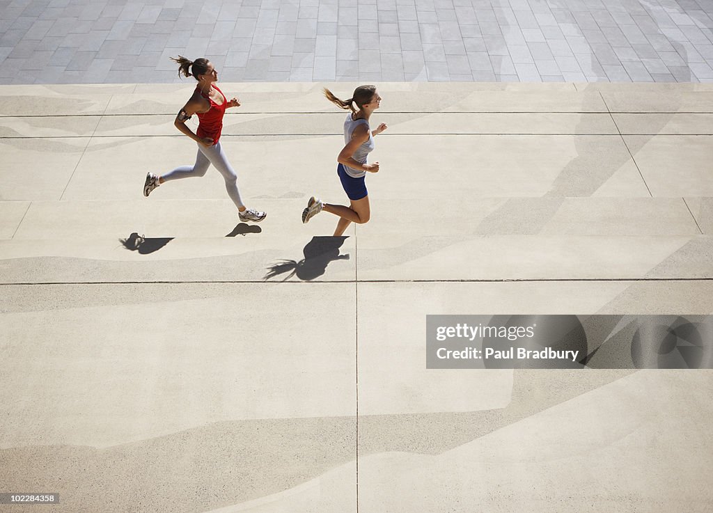 Friends running along urban sidewalk