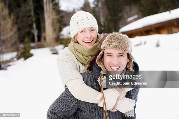 man giving girlfriend piggyback ride in snow - piggyback stock pictures, royalty-free photos & images