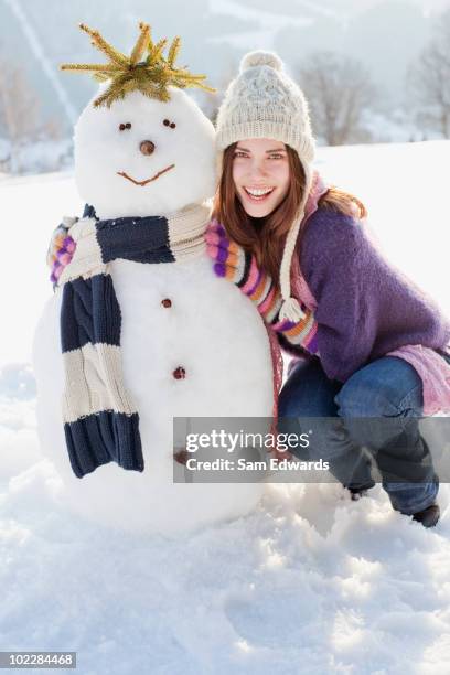 frau hockend nahe schneemann - frau schneemann stock-fotos und bilder