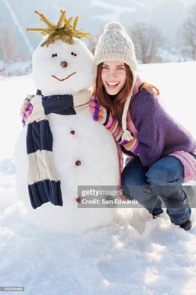 Mulher Agachar-se perto de Boneco de neve