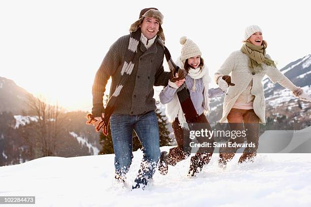 family running outdoors in snow - father and mother with their daughter playing in the snow stock pictures, royalty-free photos & images