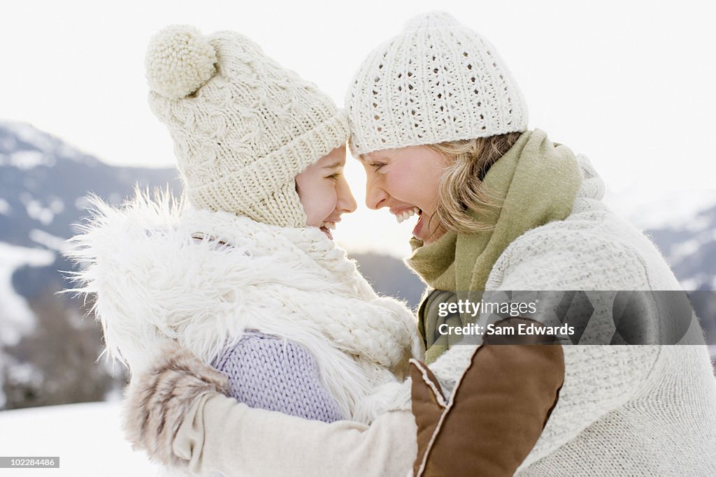 Mother and daughter hugging outdoors in snow