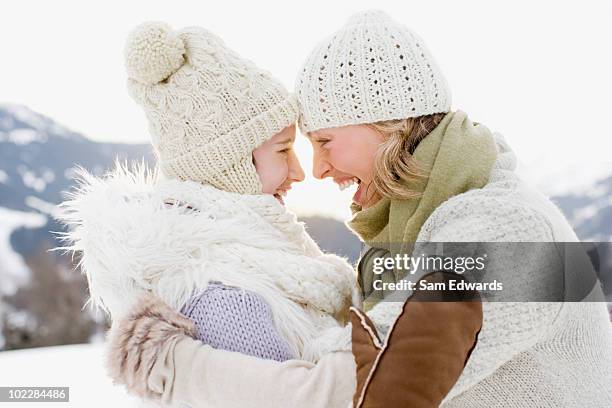 mother and daughter hugging outdoors in snow - mature woman winter stock pictures, royalty-free photos & images