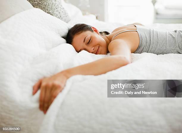 happy woman laying on bed - bed foto e immagini stock
