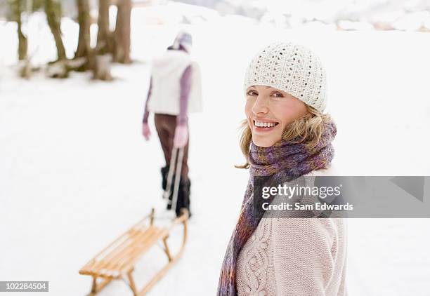 mother and daughter pulling sled through snow - mature woman winter stockfoto's en -beelden