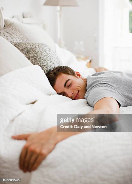 happy man laying on bed - sleeping man foto e immagini stock